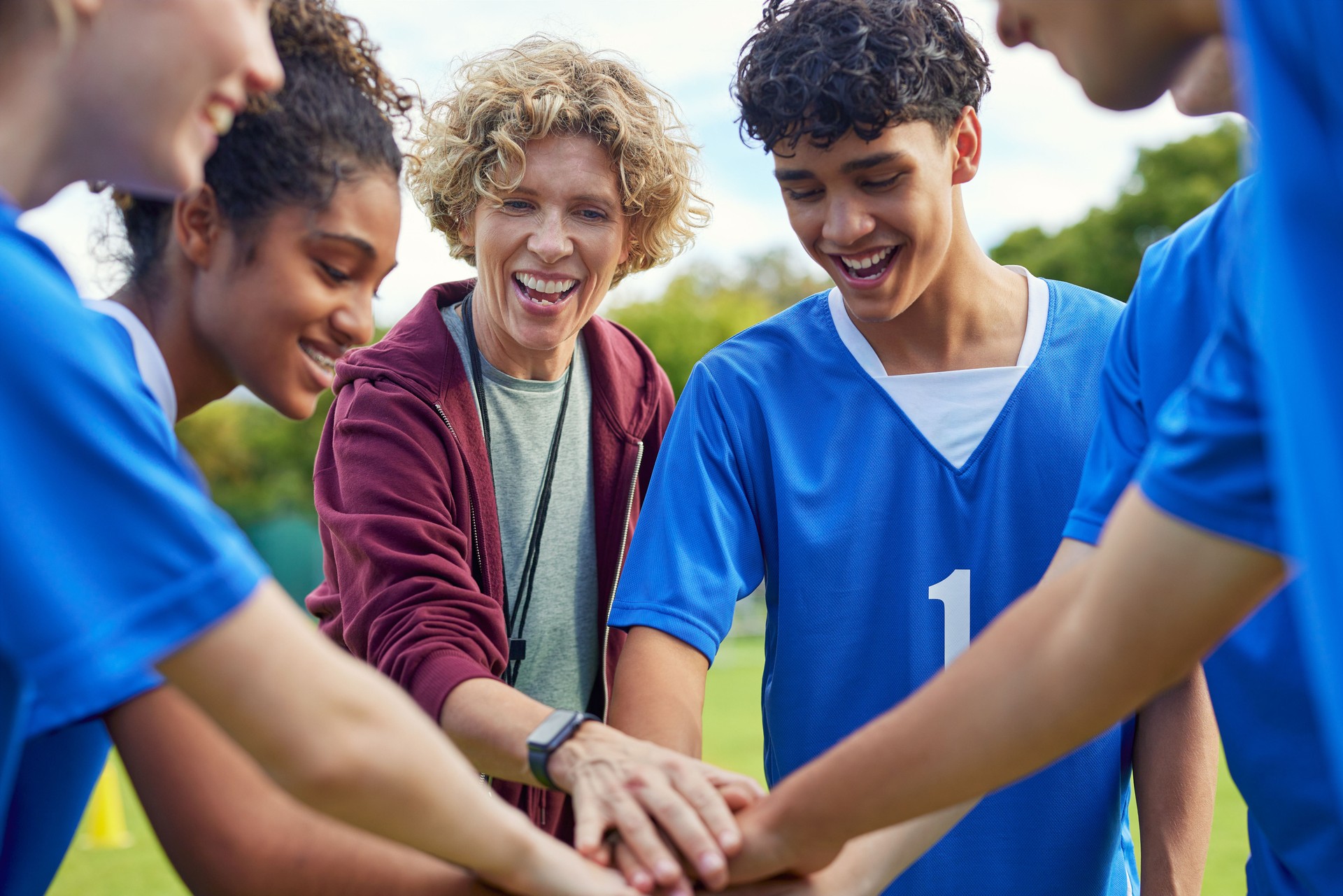 Sports team stacking hands before playing football match